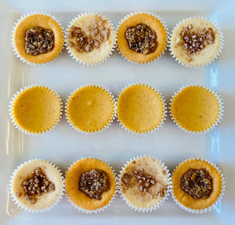 twelve assorted Fall flavored bite-sized Cheesecakes featuring Sweet Potato Pecan, Pumpkin Spice, and Apple Pie Streusel on a white platter – perfect autumn gatherings