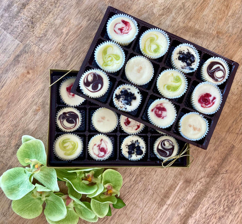 Two dozen assorted signature cheesecake minis in a gift box sitting on a table.