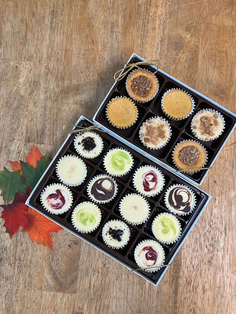 An 18 piece assortment of mini cheesecakes in a gift box on a table