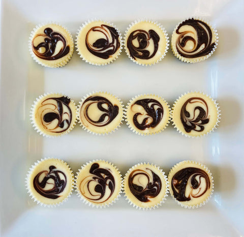 One dozen marbled ganache cheesecake minis assorted on a white plate