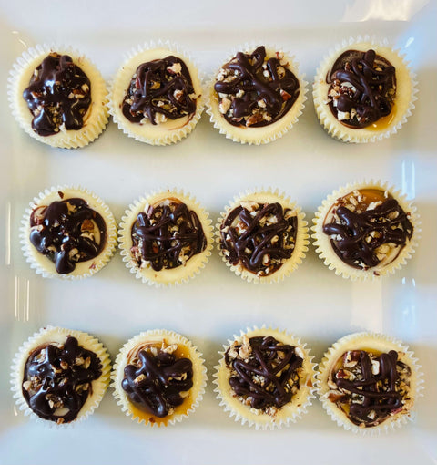 One dozen turtle cheesecake minis arranged on a white plate
