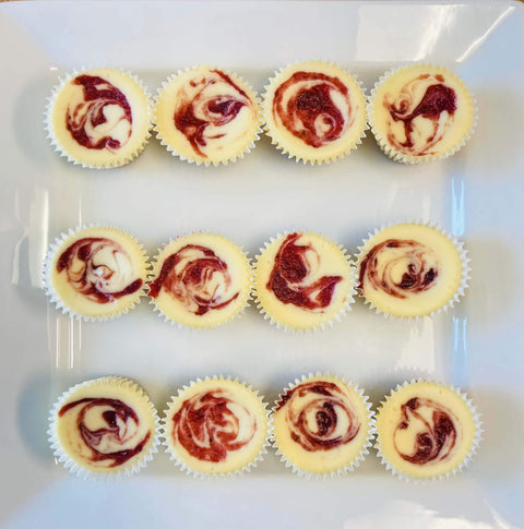 One dozen strawberry swirl cheesecake minis arranged on a white platter
