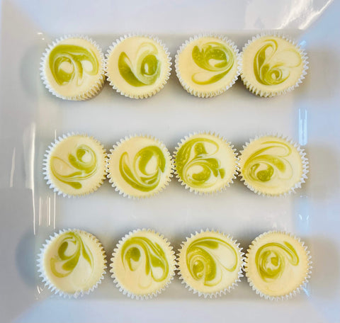 A dozen marbled key lime cheesecake minis arranged on a white platter