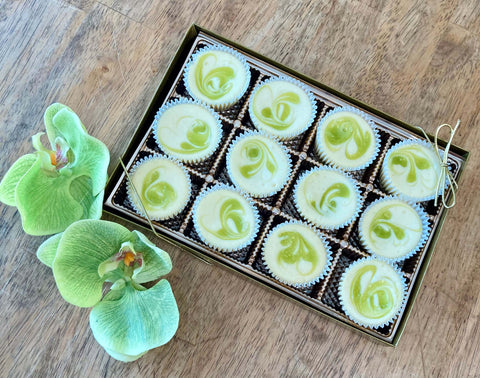 One dozen key lime cheesecake minis in a gift box sitting on a table