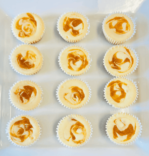 1 dozen peaches and cream cheesecake minis sitting on a white plate, top down view