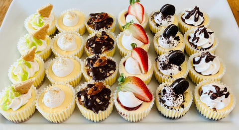 Assorted mini cheesecakes with different toppings on a white plate.