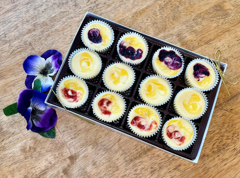 A gift box of an assortment of lemon, strawberry lemonade and blueberry lemonade mini cheesecakes