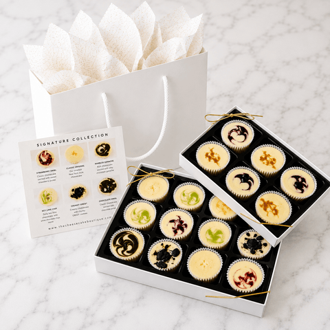 18-piece mini cheesecake gift set with open white gift box, Signature Collection flavor card, and white gift tote filled with tissue paper — perfect for gifting, birthdays, and celebrations.