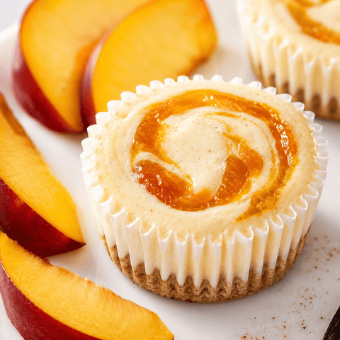 Georgia Peaches & Cream cheesecake minis with creamy filling, golden peach swirl, and fresh peach flavor on a citrus-vanilla cookie crust — The Cheesecake Boutique