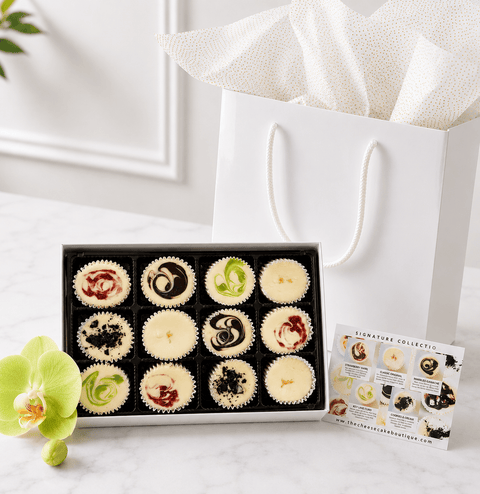 Cheesecake Gift Box – Signature Minis on a table next to a gift bag and flavor card, handcrafted in Fayetteville, GA