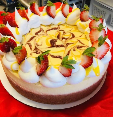 Side view of a Strawberry Lemonade whole cheesecake atop a red tablecloth.