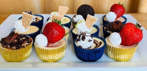 Assorted cheesecake dessert cups with whipped cream,strawberries and cookies on a white tray.
