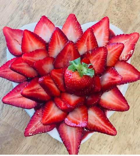 heart shaped strawberry topped cheesecake with strawberries arranged in a floral pattern