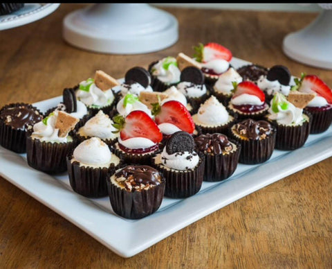 Assorted garnished cheesecake minis on a white platter