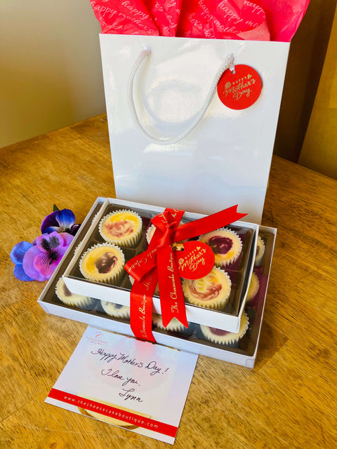 Gift box of 18 mini cheesecakes on a table, filled with fruit, cookie, and chocolate-based cheesecake flavors