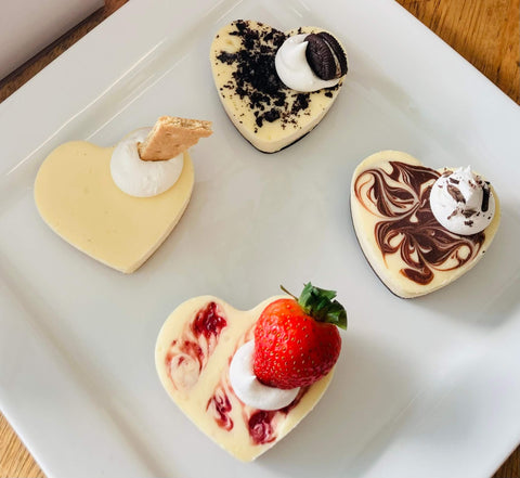 Heart-shaped desserts on a white plate with a wooden surface underneath
