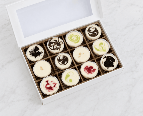 Box of 12 assorted mini cheesecakes on a light gray background
