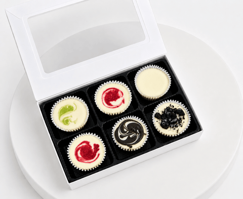 A gift Box of six mini cheesecakes on a white plate
