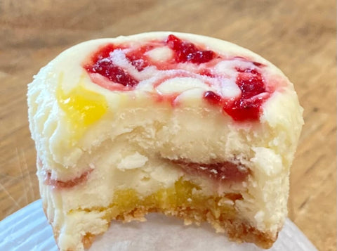 Half-eaten cheesecake with fruit filling on a wooden surface