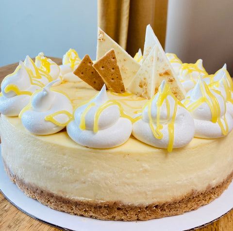 A side view of our 9-inch whole Marbled Lemon Curd cheesecake sitting on a wooden table.